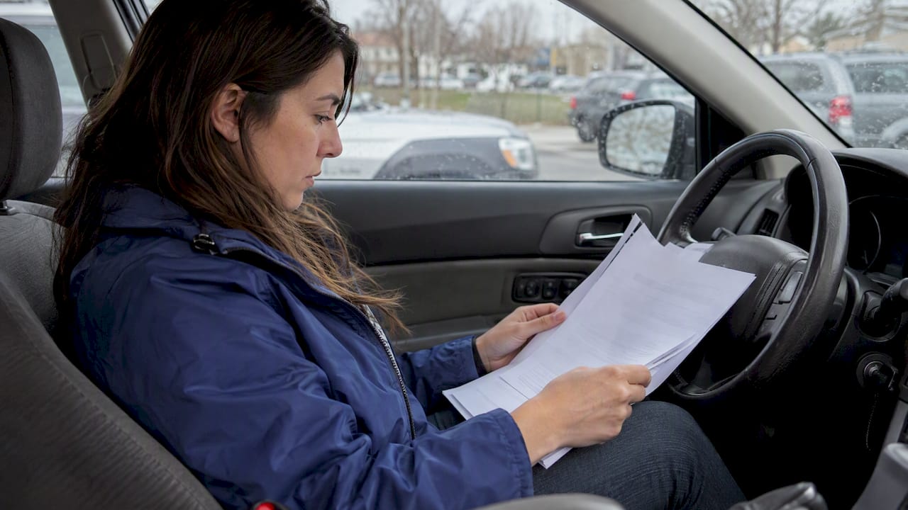 Driver reviewing an auto policy in a parked car